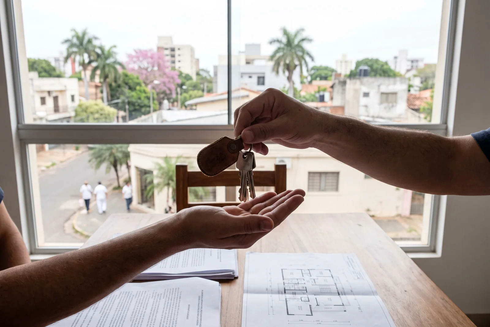 A set of house keys being handed over above property documents