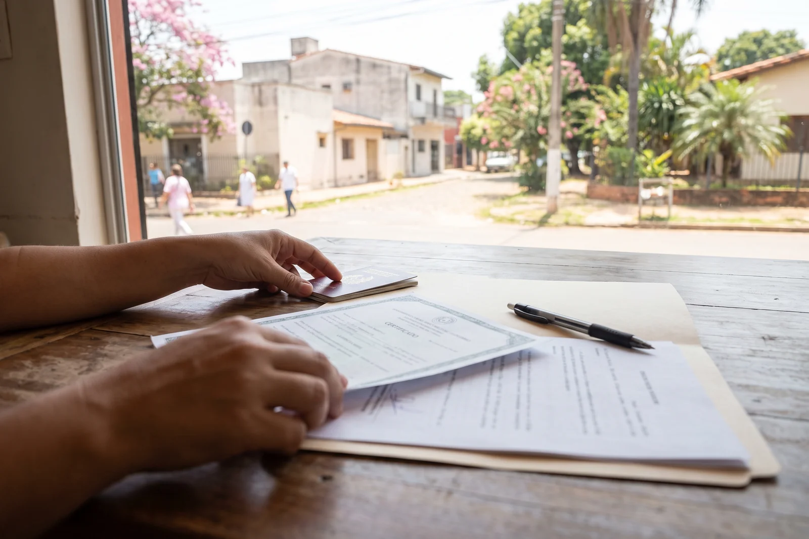 A passport, printed documents and a folder laid out on a table for a residency application