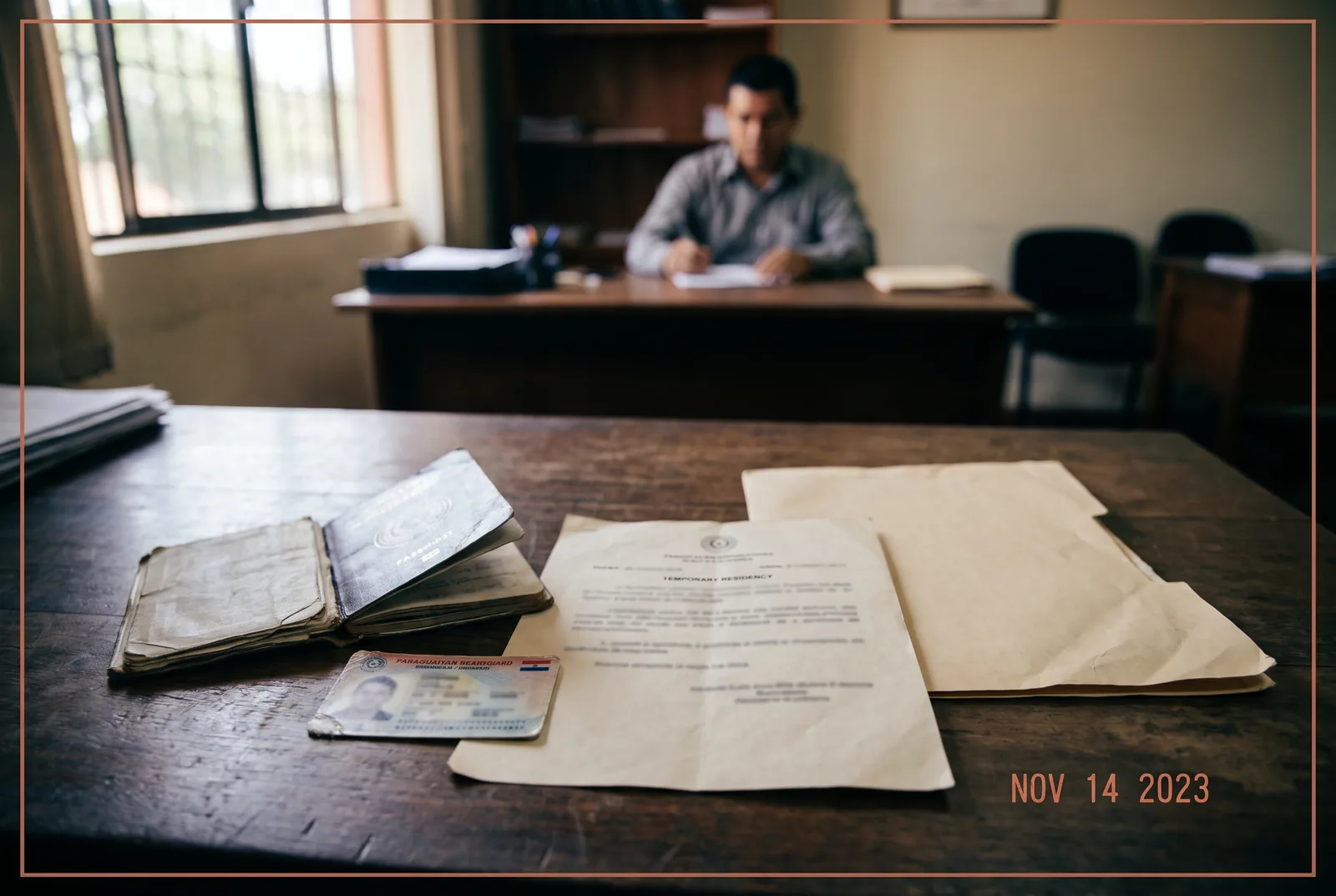 A temporary residency card and Paraguayan cedula laid on a desk beside a passport in an immigration office in Asuncion, Paraguay