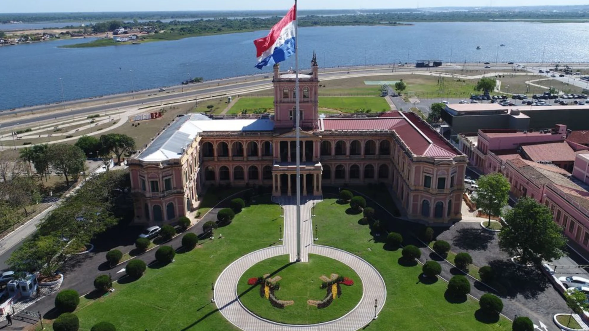 The Palacio de Lopez presidential palace in Asuncion, white colonial facade with palm trees and the modern city skyline behind it, Paraguay
